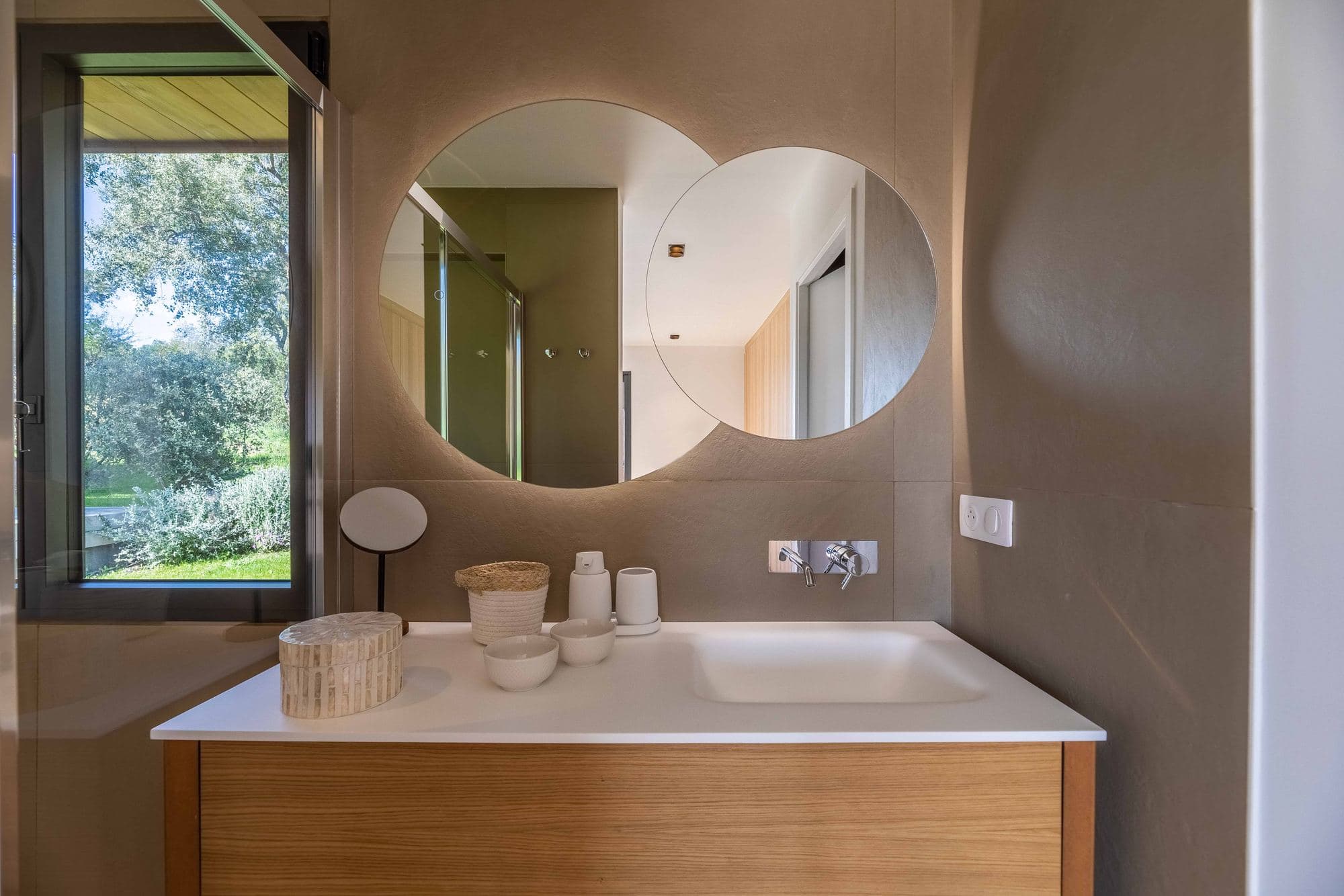 Bathroom with round mirror and window onto the grounds
